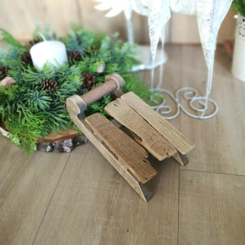 Male sanki dekoracyjne przy swiatecznym stroiku.