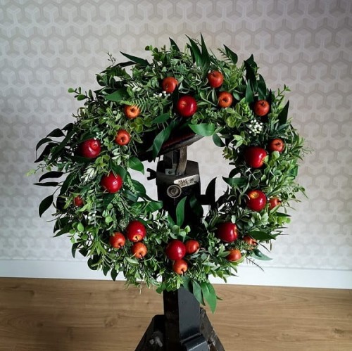 Jesienny, zielony wianek z małymi, czerwonymi jabłkami