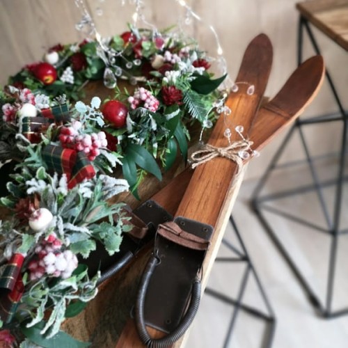 Narty z  drewna w kolorze naturalnym  do dekoracji i wianek świąteczny z czerwonymi dodatkami